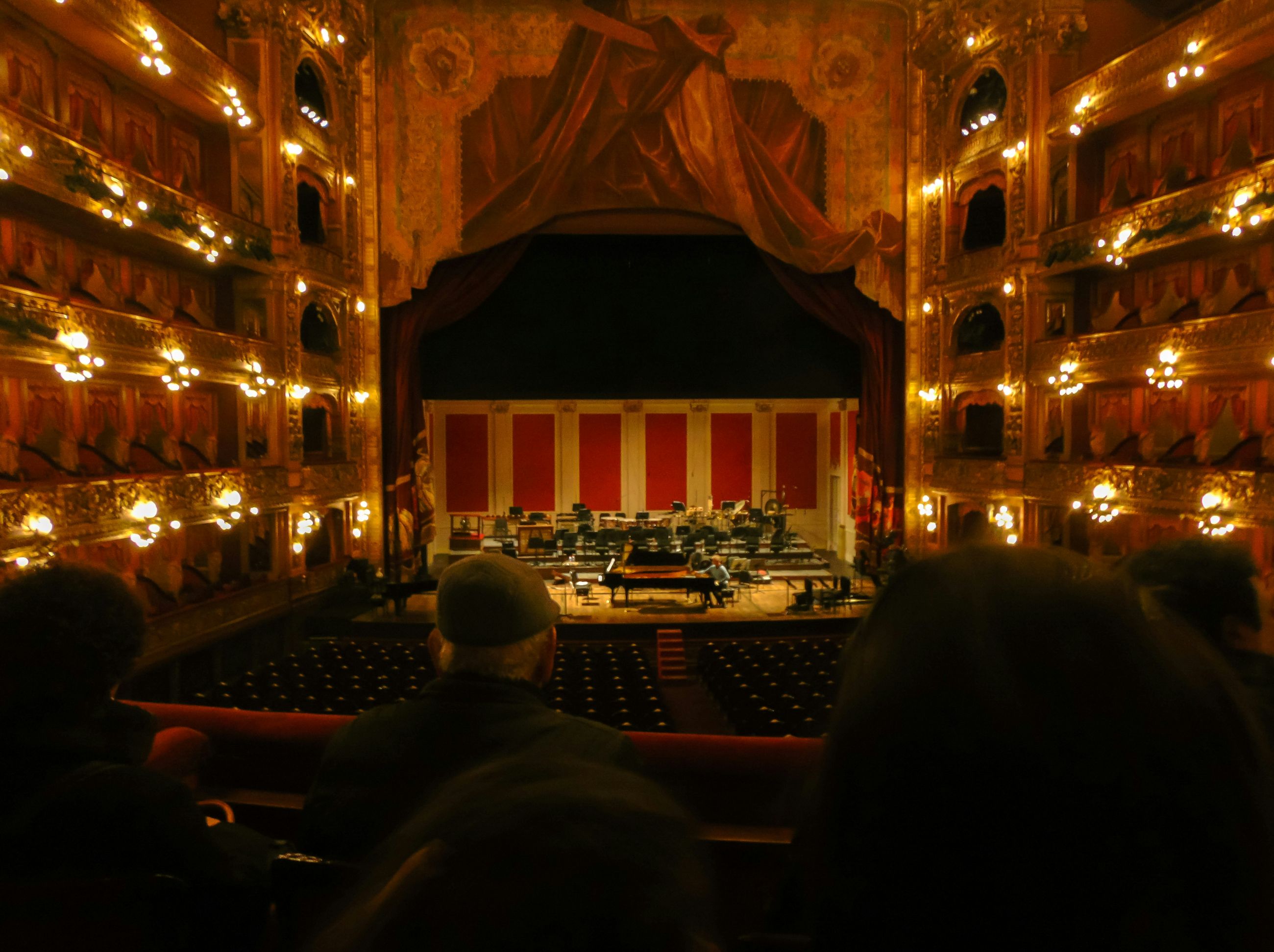 Performing arts centre auditorium viewed from the rear stalls, stage lit in blue, full house